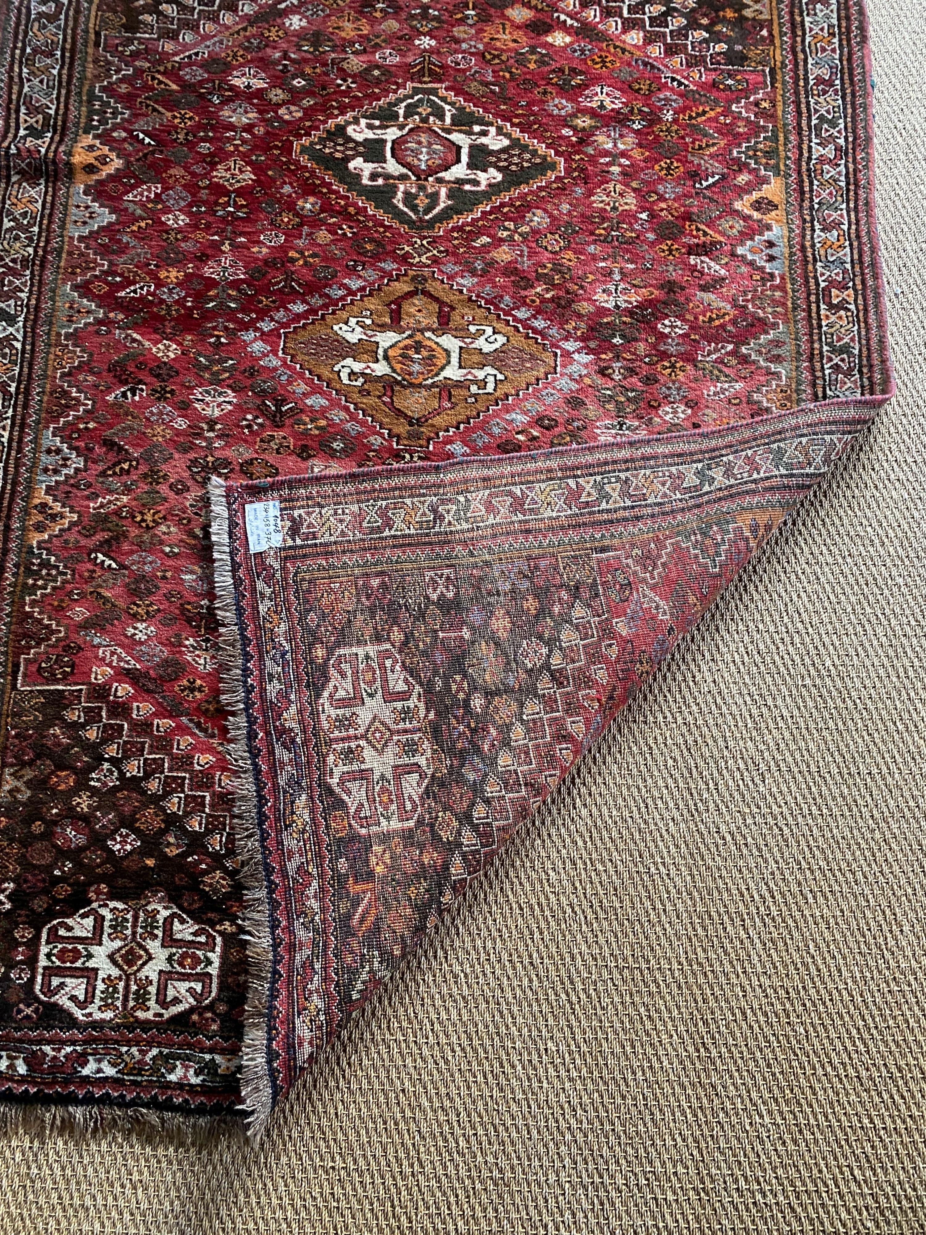 A Persian red ground rug, with three central hectagons and floral borders, 236 x 161cm